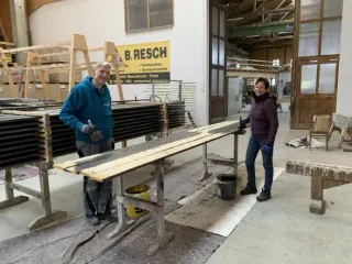 Vereinsmitglieder streichen die Außenschalung, Sparren und Pfetten in der Zimmerei