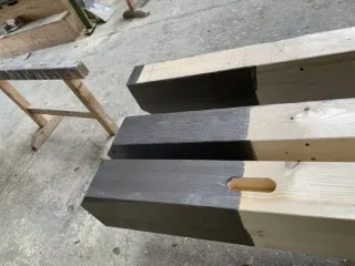 Vereinsmitglieder streichen die Außenschalung, Sparren und Pfetten in der Zimmerei